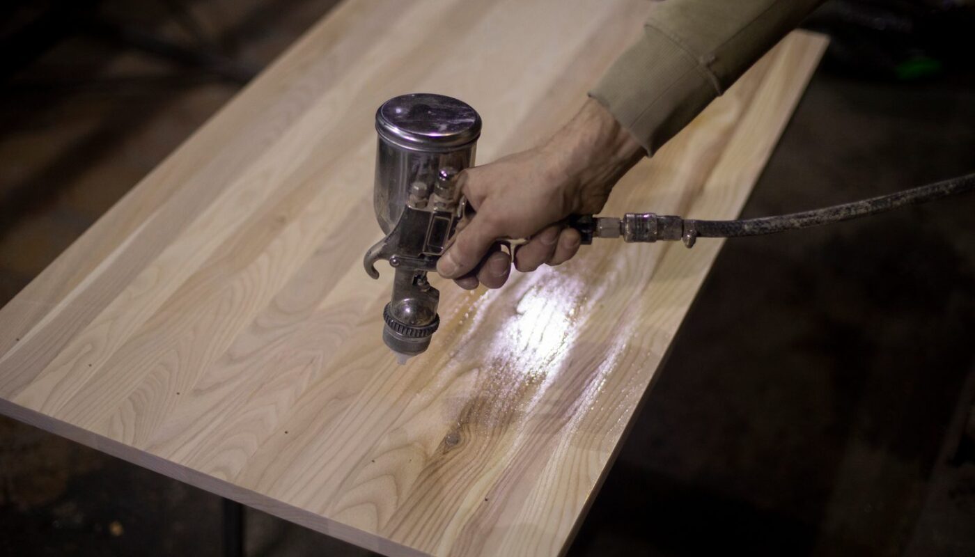 Artisan aérogommant un meuble en bois dans un atelier professionnel.